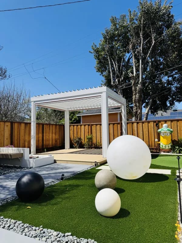 White pergola over a play area with oversized decorative spheres