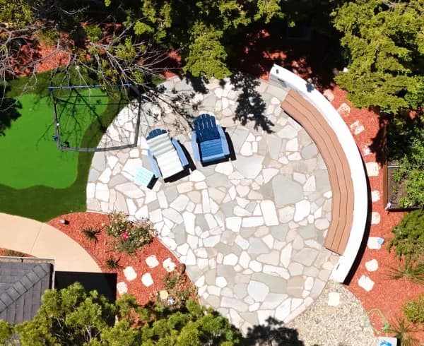 Overhead view of a circular flagstone patio with a curved seat wall