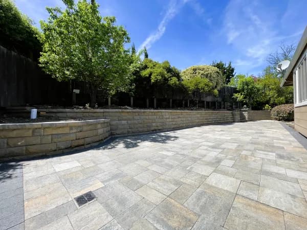 Wide paver patio bordered by a low stone retaining wall