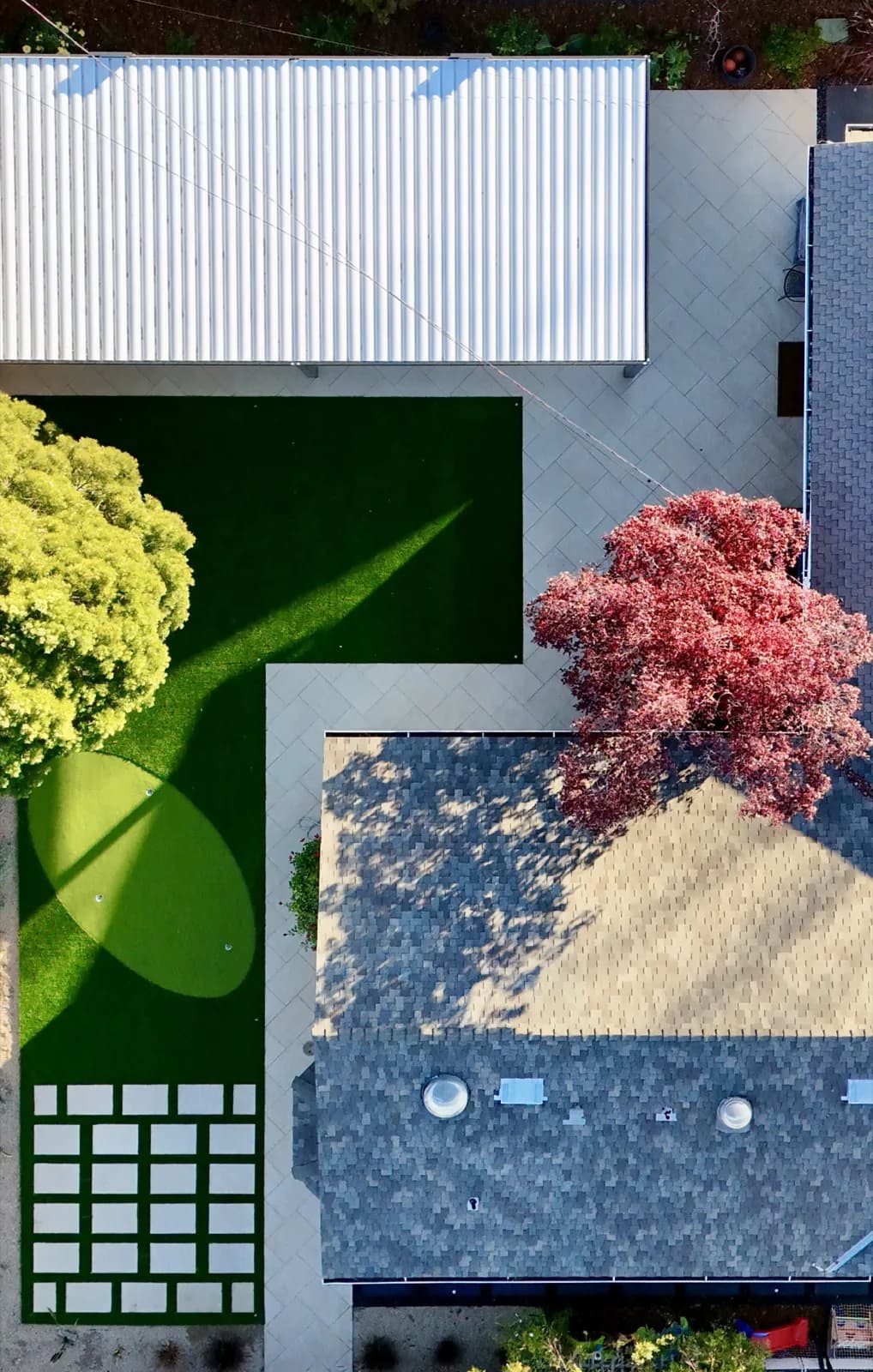 Drone view of a backyard with turf, a paver patio and a grid of stepping pads