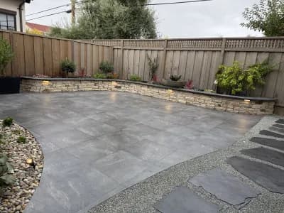 Curved concrete patio with a lit low retaining wall and gravel border