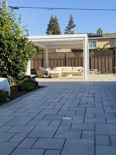 Large-format grey paver patio with a white pergola and outdoor sectional