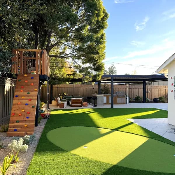 Backyard with turf, a climbing structure, outdoor kitchen and pergola