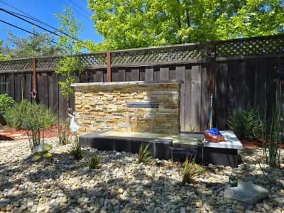 Stacked stone water feature set into a gravel dry creek bed